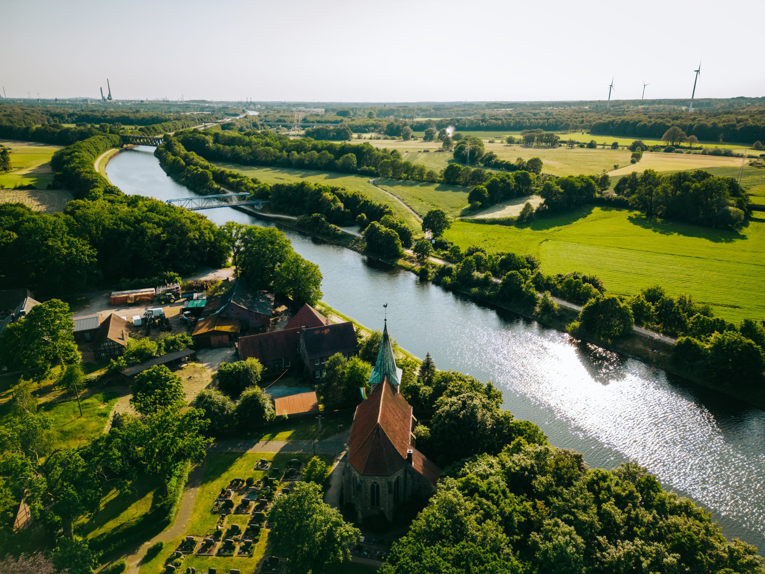 Summer aerial drone view landscape navigable river with bridges, agricultural fields and forests and farmers houses in Germany countryside.